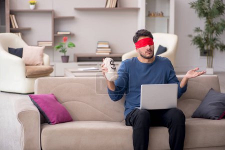 Photo for Blindfolded man holding moneybag at home - Royalty Free Image