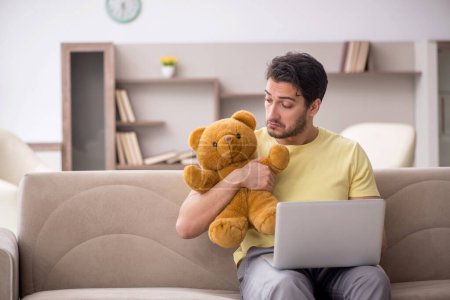 Photo for Young male student hugging toy bear at home - Royalty Free Image