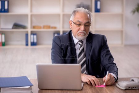 Téléchargez les photos : Vieil homme d'affaires employé travaillant sur le lieu de travail - en image libre de droit