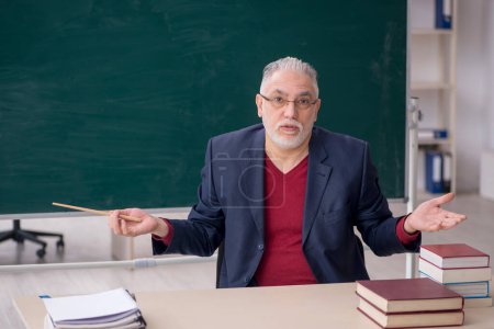 Téléchargez les photos : Old teacher sitting in the classroom - en image libre de droit