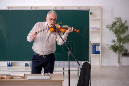 Téléchargez les photos : Vieil enseignant jouant du violon en classe - en image libre de droit