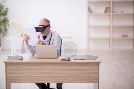 Téléchargez les photos : Old doctor wearing virtual glasses at the hospital - en image libre de droit