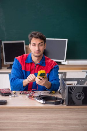 Photo for Young repairman repairing computers in the classroom - Royalty Free Image