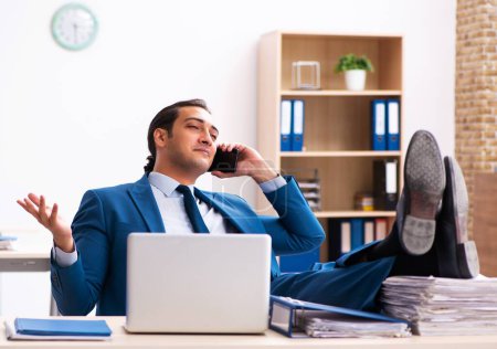 Téléchargez les photos : Jeune homme d'affaires employé assis dans le bureau - en image libre de droit