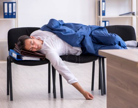 Photo for Young employee sleeping in the office on chairs - Royalty Free Image