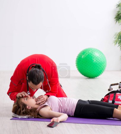 Photo for The paramedic in red visiting young woman in gym - Royalty Free Image