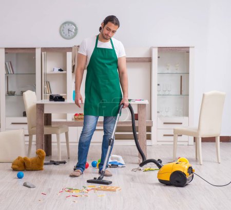 Téléchargez les photos : Jeune entrepreneur nettoyage de l'appartement après la fête des enfants - en image libre de droit