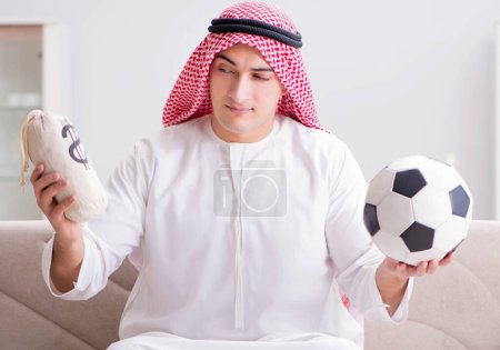 Téléchargez les photos : Le jeune homme arabe regardant le football assis sur le canapé - en image libre de droit