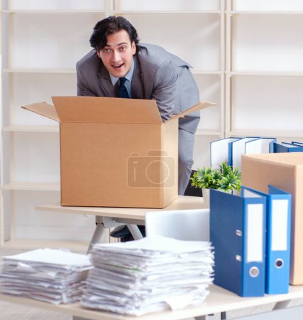 Téléchargez les photos : The young man employee with boxes in the office - en image libre de droit