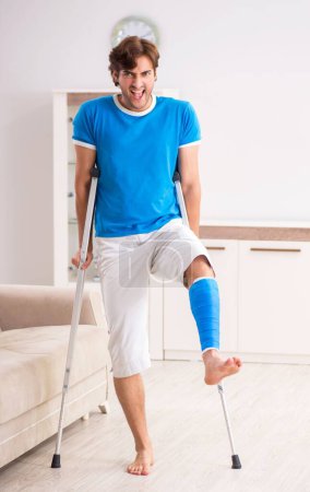 Photo for The leg injured young man with crutches at home - Royalty Free Image