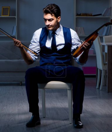 Téléchargez les photos : Le jeune musicien pratiquant le violon à la maison - en image libre de droit