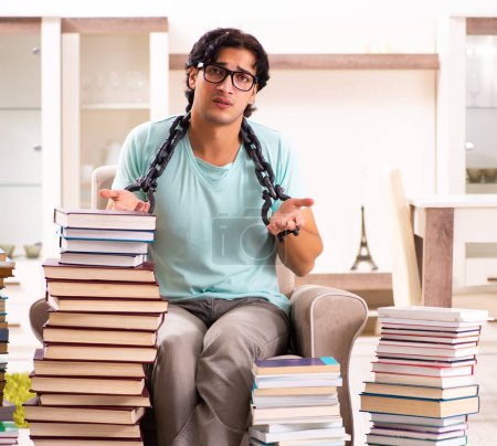 Foto de El estudiante masculino con muchos libros en casa - Imagen libre de derechos
