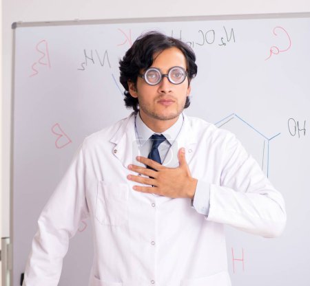 Photo for The young funny chemist in front of white board - Royalty Free Image