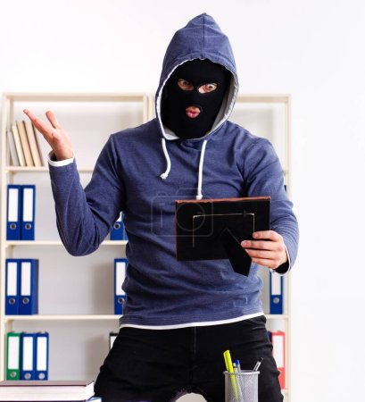 Téléchargez les photos : Le voleur masculin dans la cagoule dans le bureau - en image libre de droit