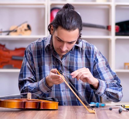 Photo for The young handsome repairman repairing violin - Royalty Free Image