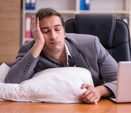 Téléchargez les photos : Jeune employé dormant sur le lieu de travail - en image libre de droit