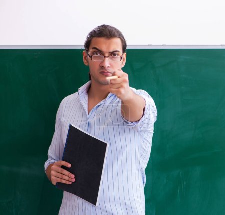 Photo for Young teacher in front of blackboard - Royalty Free Image