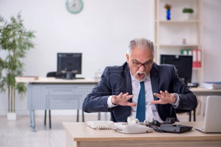 Téléchargez les photos : Vieil homme d'affaires employé parlant au téléphone dans le bureau - en image libre de droit