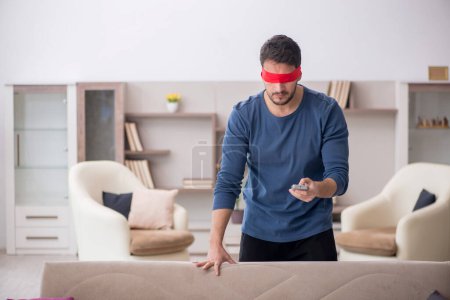 Photo for Blindfolded man watching tv at home - Royalty Free Image