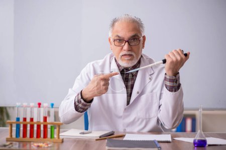Téléchargez les photos : Old teacher chemist sitting in the classroom - en image libre de droit
