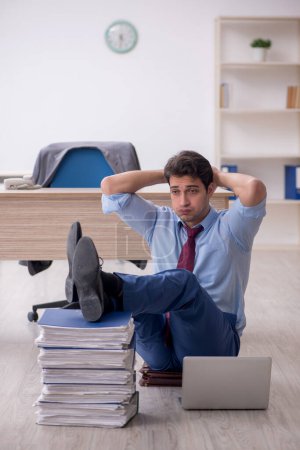 Foto de Young employee unhappy with excessive work at workplace - Imagen libre de derechos