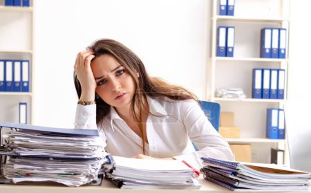 Téléchargez les photos : The young female employee unhappy with excessive work - en image libre de droit