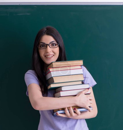 Photo for The young female teacher student in front of green board - Royalty Free Image