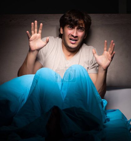 Foto de El joven asustado en su cama teniendo pesadillas - Imagen libre de derechos