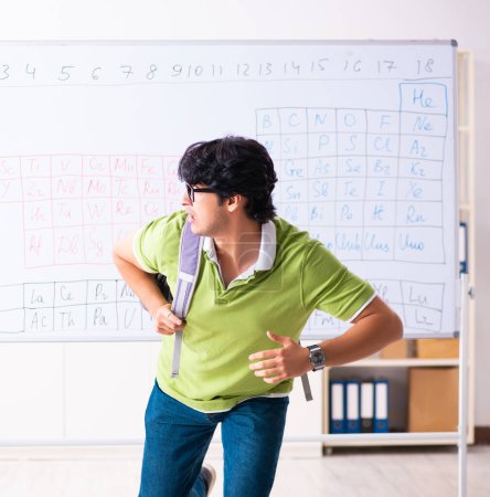 Foto de El joven estudiante químico en frente de la tabla periódica - Imagen libre de derechos