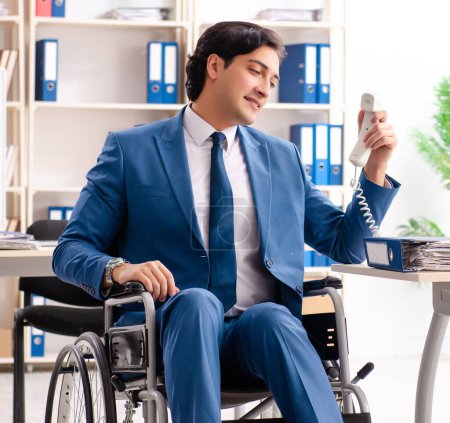Téléchargez les photos : L'employé masculin en fauteuil roulant travaillant au bureau - en image libre de droit