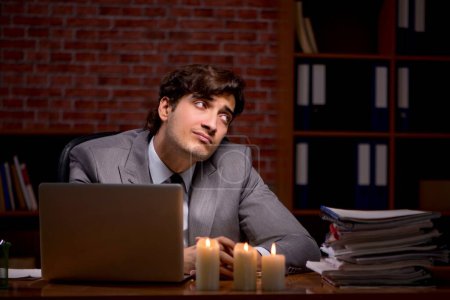 Foto de El hombre de negocios trabajando hasta tarde en la oficina con la luz de las velas - Imagen libre de derechos