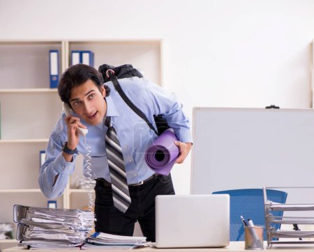 Téléchargez les photos : The young handsome male employee doing exercises in the office - en image libre de droit