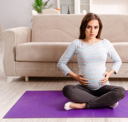 Photo for The young pregnant woman doing sport exercises at home - Royalty Free Image