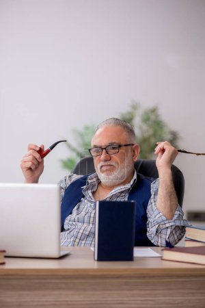 Téléchargez les photos : Vieil écrivain assis sur le lieu de travail - en image libre de droit