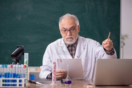 Téléchargez les photos : Old teacher chemist sitting in the classroom - en image libre de droit
