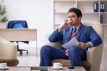 Téléchargez les photos : Jeune homme d'affaires assis sur le lieu de travail - en image libre de droit