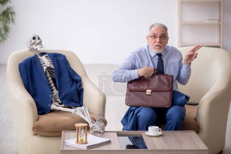 Téléchargez les photos : Vieux patron masculin et squelette dans le concept de réunion d'affaires - en image libre de droit