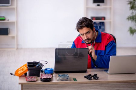 Photo for Young repairman repairing computer at workshop - Royalty Free Image