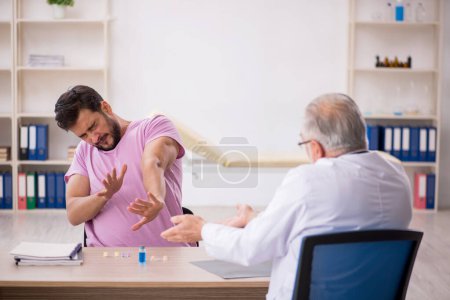 Foto de Paciente joven visitando viejo médico masculino - Imagen libre de derechos