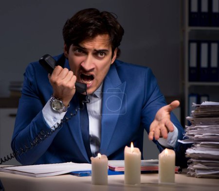 Téléchargez les photos : L'homme d'affaires travaillant tard dans le bureau avec de la lumière de bougie - en image libre de droit