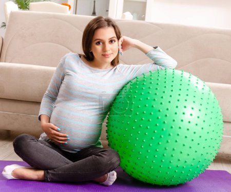 Foto de La joven embarazada haciendo ejercicios deportivos en casa - Imagen libre de derechos