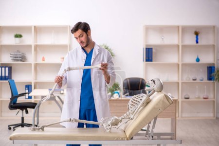 Foto de Joven doctor con esqueleto en el hospital - Imagen libre de derechos