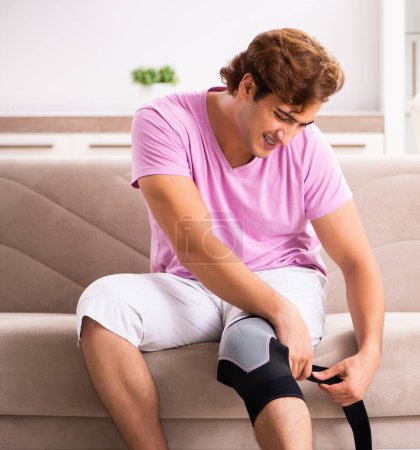 Foto de El joven con la rodilla lesionada recuperándose en casa - Imagen libre de derechos