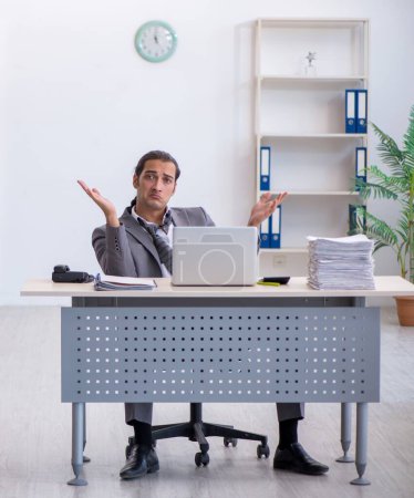Photo for Young employee unhappy with excessive work in the office - Royalty Free Image