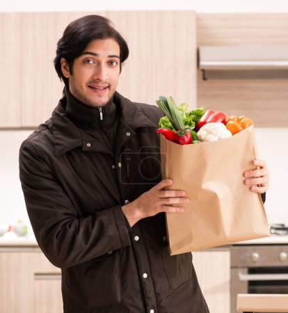 Photo for The young handsome man with vegetables in the kitchen - Royalty Free Image