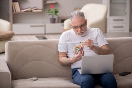 Téléchargez les photos : Vieil homme tenant verre avec des pilules à la maison - en image libre de droit