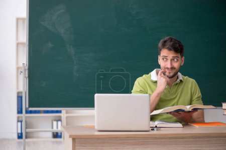 Photo for Young student sitting in front of green board - Royalty Free Image