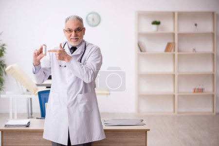 Téléchargez les photos : Old doctor suggesting pills at the hospital - en image libre de droit