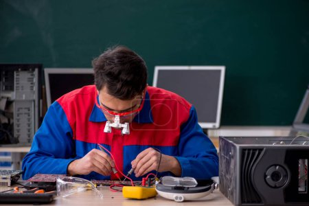 Foto de Joven reparador reparando computadoras en el aula - Imagen libre de derechos