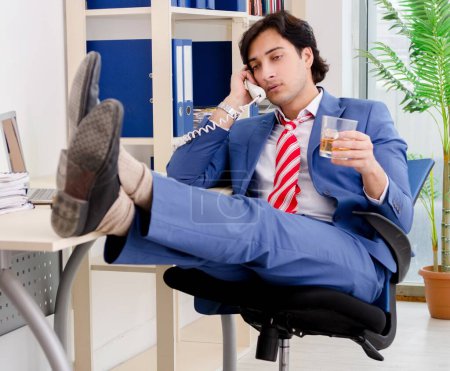 Photo for Young businessman employee drinking in office - Royalty Free Image